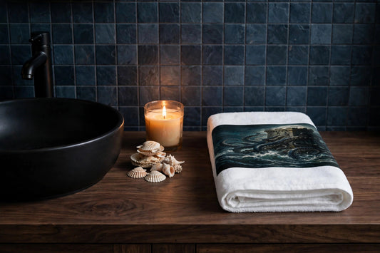 The Kraken's Embrace hand towel folded on a dark wood vanity beside a black vessel sink with a lit candle and seashells