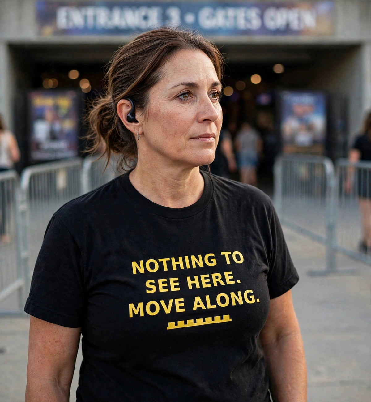Woman wearing the Nothing To See Here t-shirt at a venue entrance, full print visible