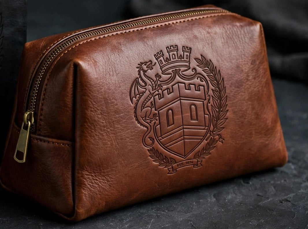 Sovereign Crest brown leather toiletry bag with engraved crest, staged on dark slate