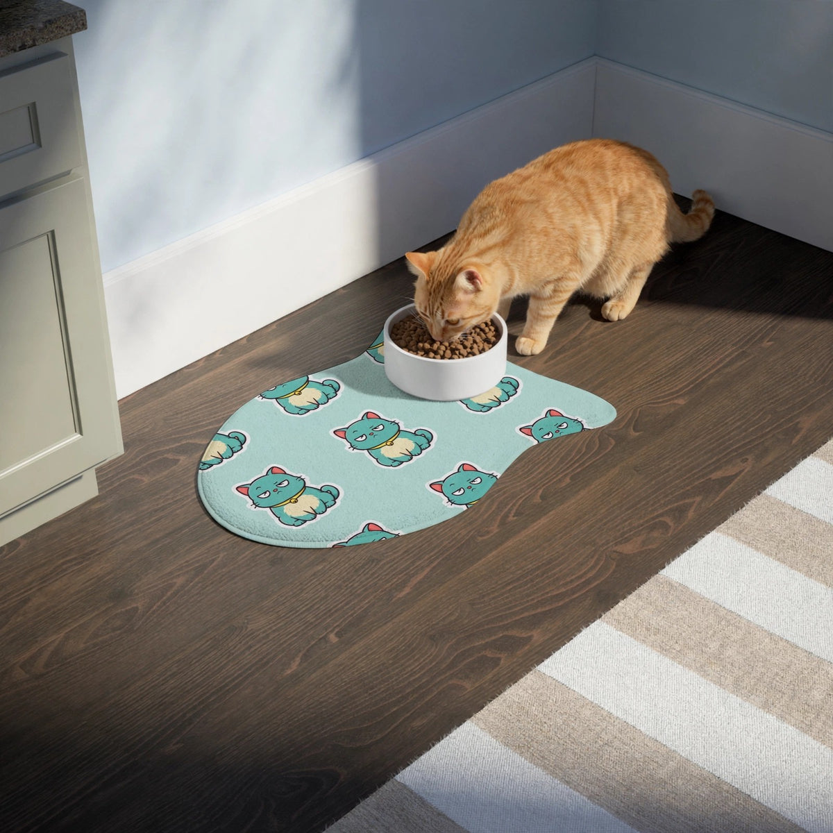 A cat eating from a bowl on the fish-shaped Catch of the Day feeding mat on a kitchen floor.