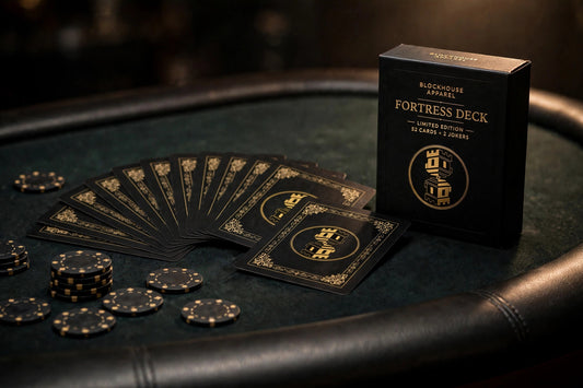 Fortress Deck tuck box and a fan of cards showing the black and gold two-way tower card back, on a poker table with chips
