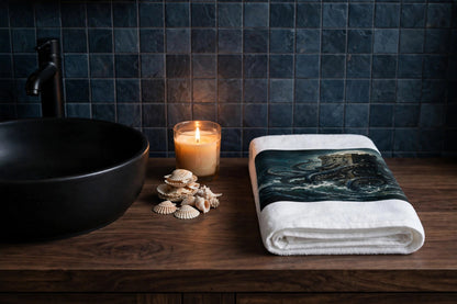 The Kraken's Embrace hand towel folded on a dark wood vanity beside a black vessel sink with a lit candle and seashells