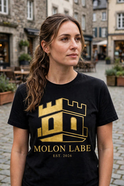 Woman wearing the black Molon Labe tee with gold castle tower logo in a town square