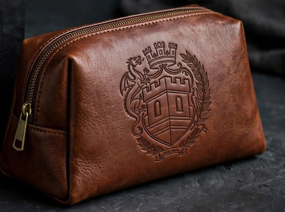 Sovereign Crest brown leather toiletry bag with engraved crest, staged on dark slate