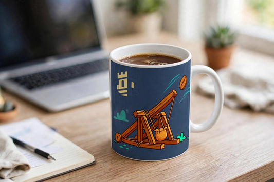 Tactical Caffeine mug filled with coffee on an office desk, catapult flinging coffee beans toward a stone tower