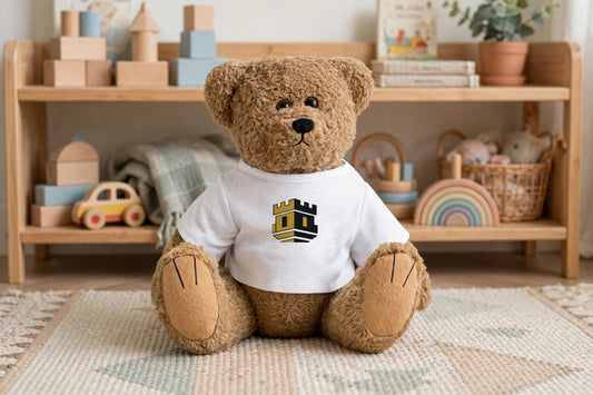 Brown teddy bear plush in its white castle logo tee sitting on a nursery rug in front of a toy shelf